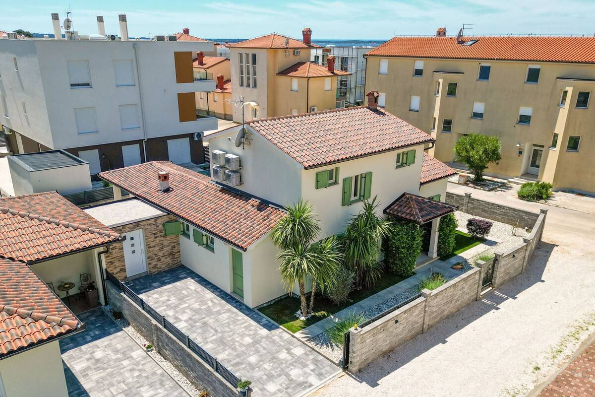 A residential area with terracotta-tiled roofs, a paved courtyard, and a stone wall.