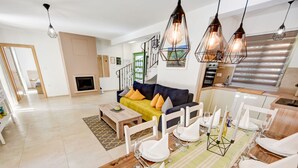 A modern living room with a sofa, dining table set for a meal, and a staircase leading to an upper level. - Guest House Gabriel (Vodnjan)