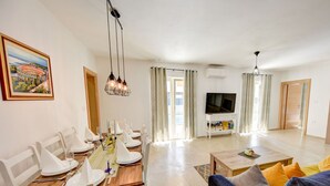 A living room with a dining area, a TV, and a painting on the wall. - Guest House Gabriel (Vodnjan)