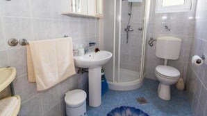 Ein Badezimmer mit Waschbecken, Toilette, Dusche und einem kleinen Mülleimer.