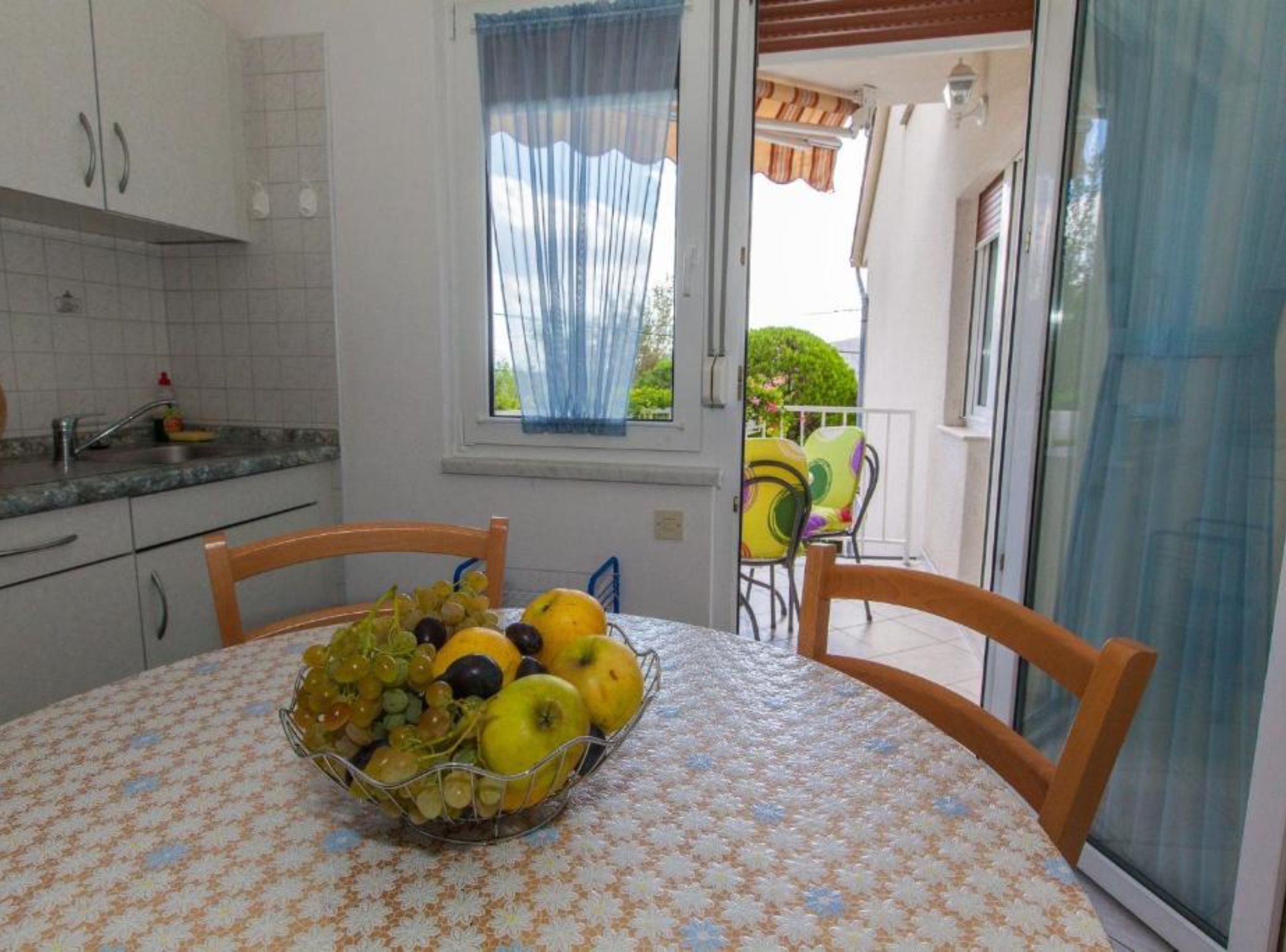 A kitchen with a dining table, chairs, and a window with curtains.