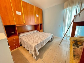 Ein Schlafzimmer mit einem Bett, einem Holzschrank und einem Fenster mit Vorhängen.