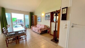 Ein Zimmer mit Esstisch, Stühlen, einer Couch, einem Spiegel und einer Tür.