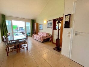 Ein Zimmer mit Esstisch, Stühlen, einer Couch, einem Spiegel und einer Tür.