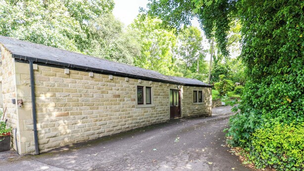 A stone building with a flat roof, a door, and a window. - The Lodge (Brighouse)