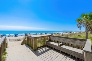 A wooden deck leading to a beach with a clear view of the ocean and beach umbrellas. - The Sail Away | Near Beach & Boardwalk (Myrtle Beach)