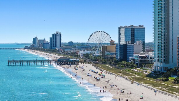 Eine Küstenstadt mit Strand, einer Mole und einem großen Riesenrad.