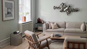 Un soggiorno con divano, due poltrone in legno, un tavolino da caffè, un elemento decorativo a parete, un quadro incorniciato e una finestra con vista.
