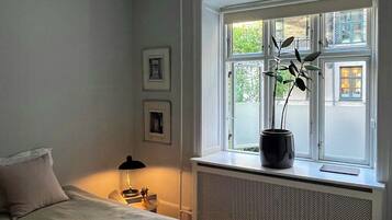 Et soveværelse med seng, et vindue med udsigt, en radiator og et natbord med lampe.