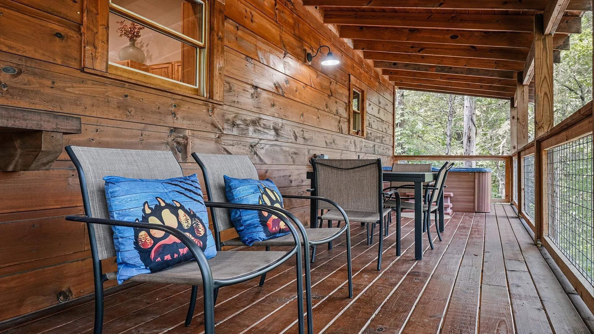 Une cabane en bois dotée d’un porche, aménagé avec des chaises et une table.