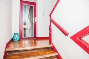 Un escalier avec des marches en bois et des rampes rouges menant Ă une porte dotĂ©e dâun panneau de verre.