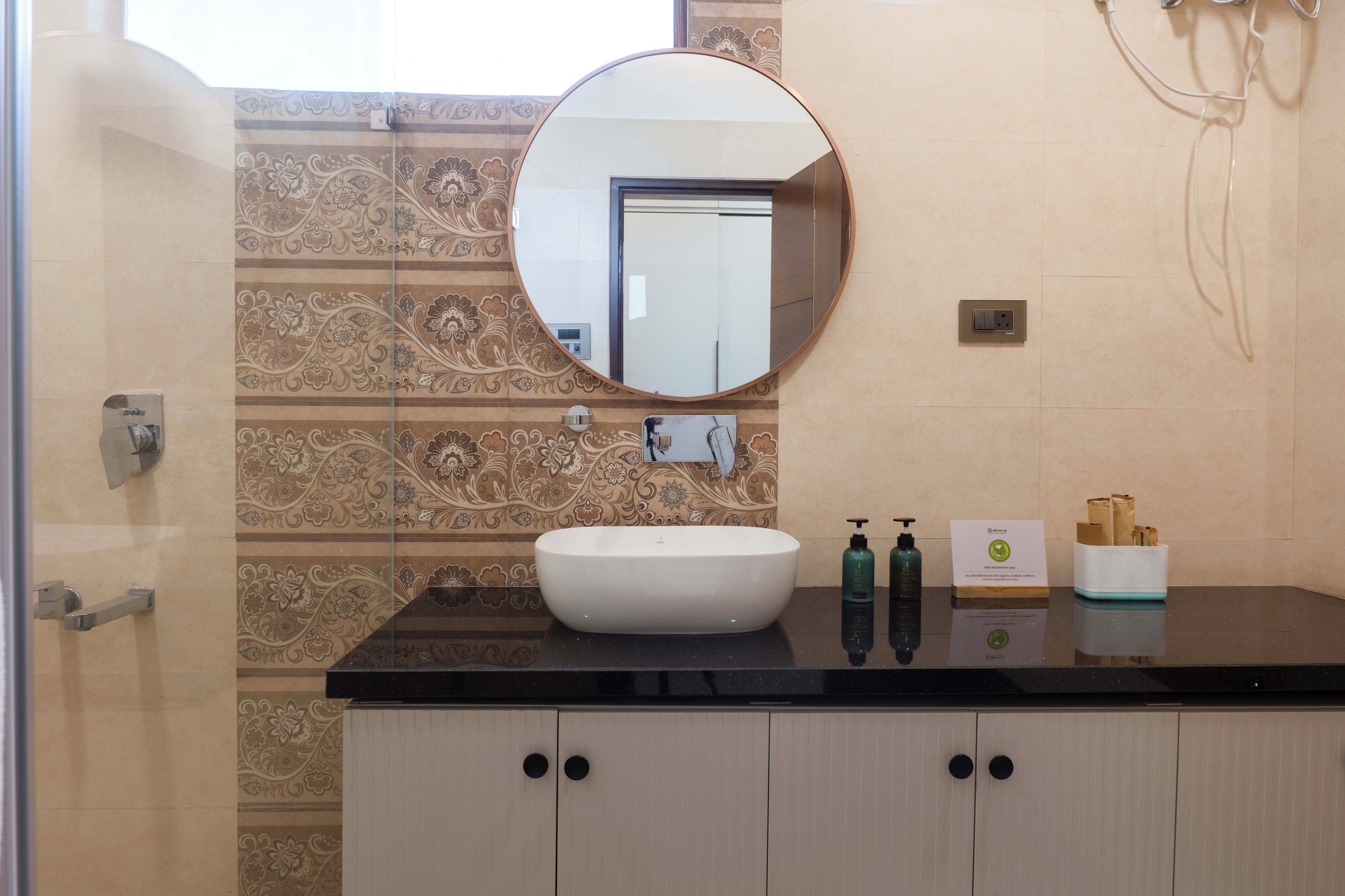 Une salle de bain avec un miroir rond, un lavabo et un meuble avec deux portes.
