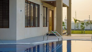 Un bâtiment moderne doté d’une piscine, de grandes fenêtres et d’un balcon.