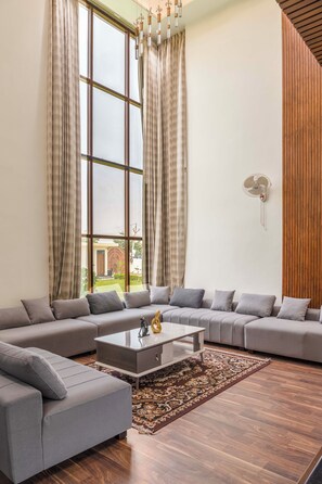 Una sala moderna con un sofá modular, una mesa de centro y un ventanal con cortinas.
