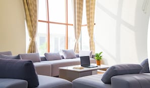 A modern living room with a sofa set, a coffee table with a laptop, and a potted plant. - ELIVAAS Lush Haven 4BHK Villa Pvt Pool (Jaipur)