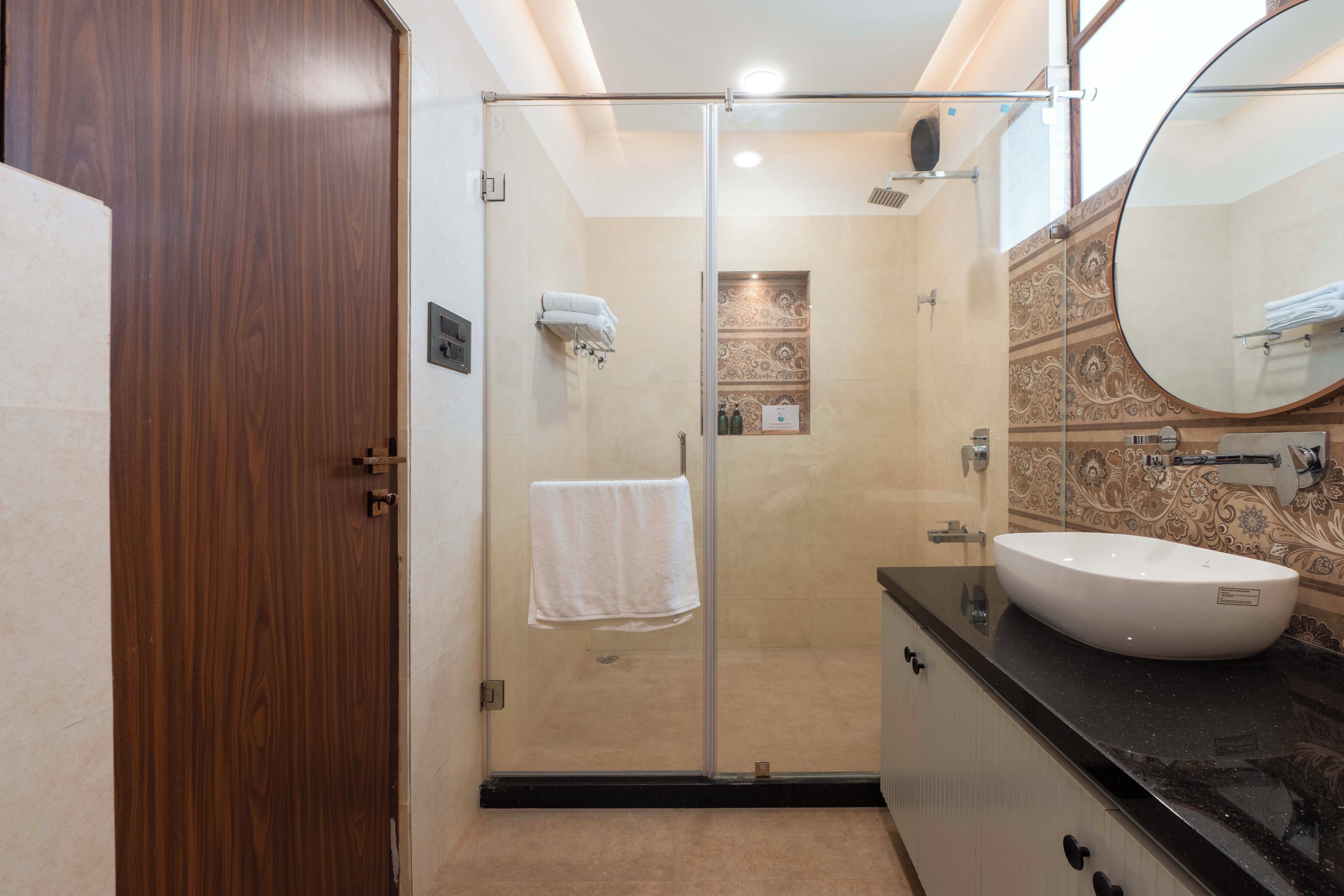 A modern bathroom with a glass-enclosed shower, a white sink, and a large mirror.