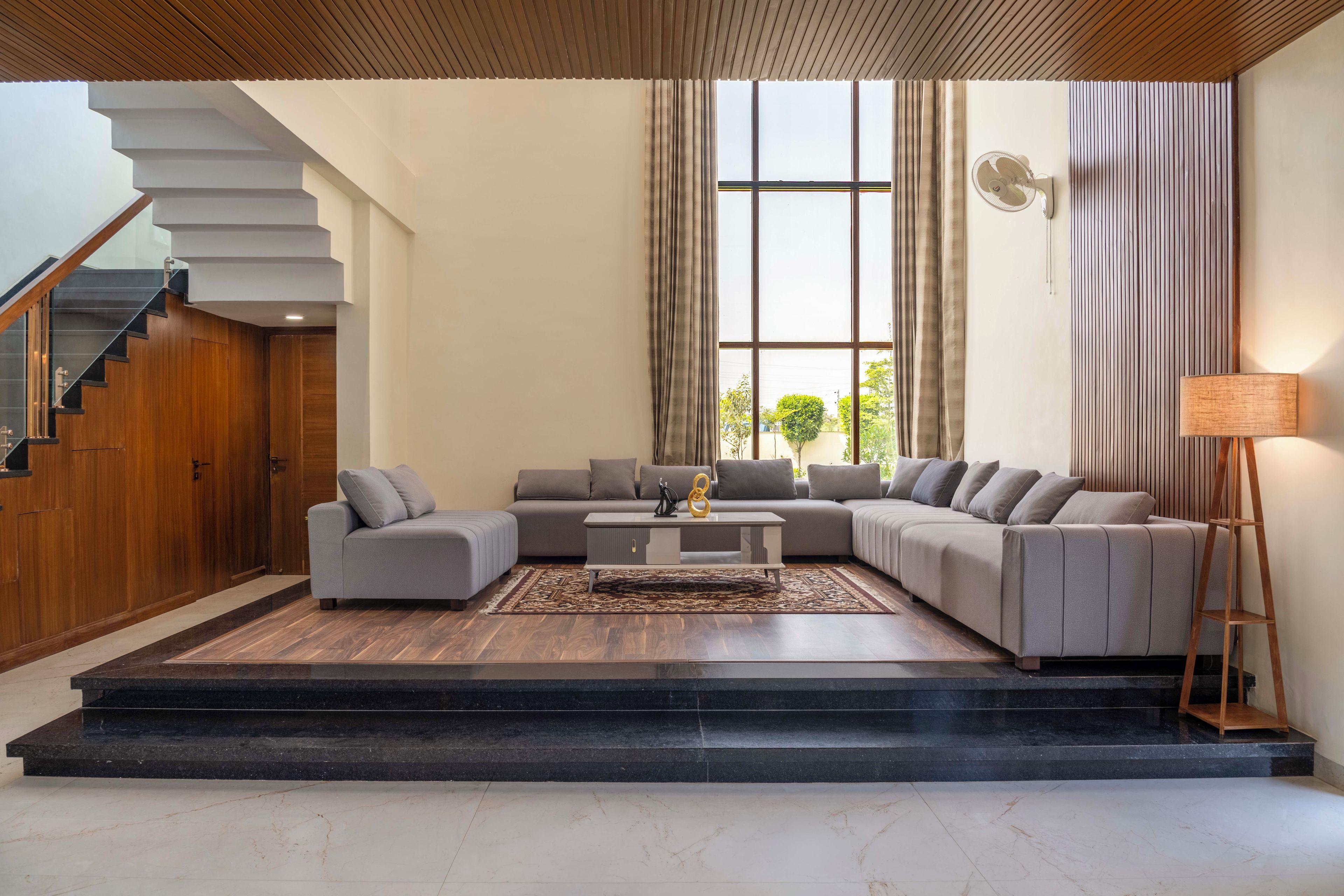 A modern living room with a sectional sofa, a coffee table, and a staircase.