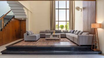 A modern living room with a sectional sofa, a coffee table, and a staircase.