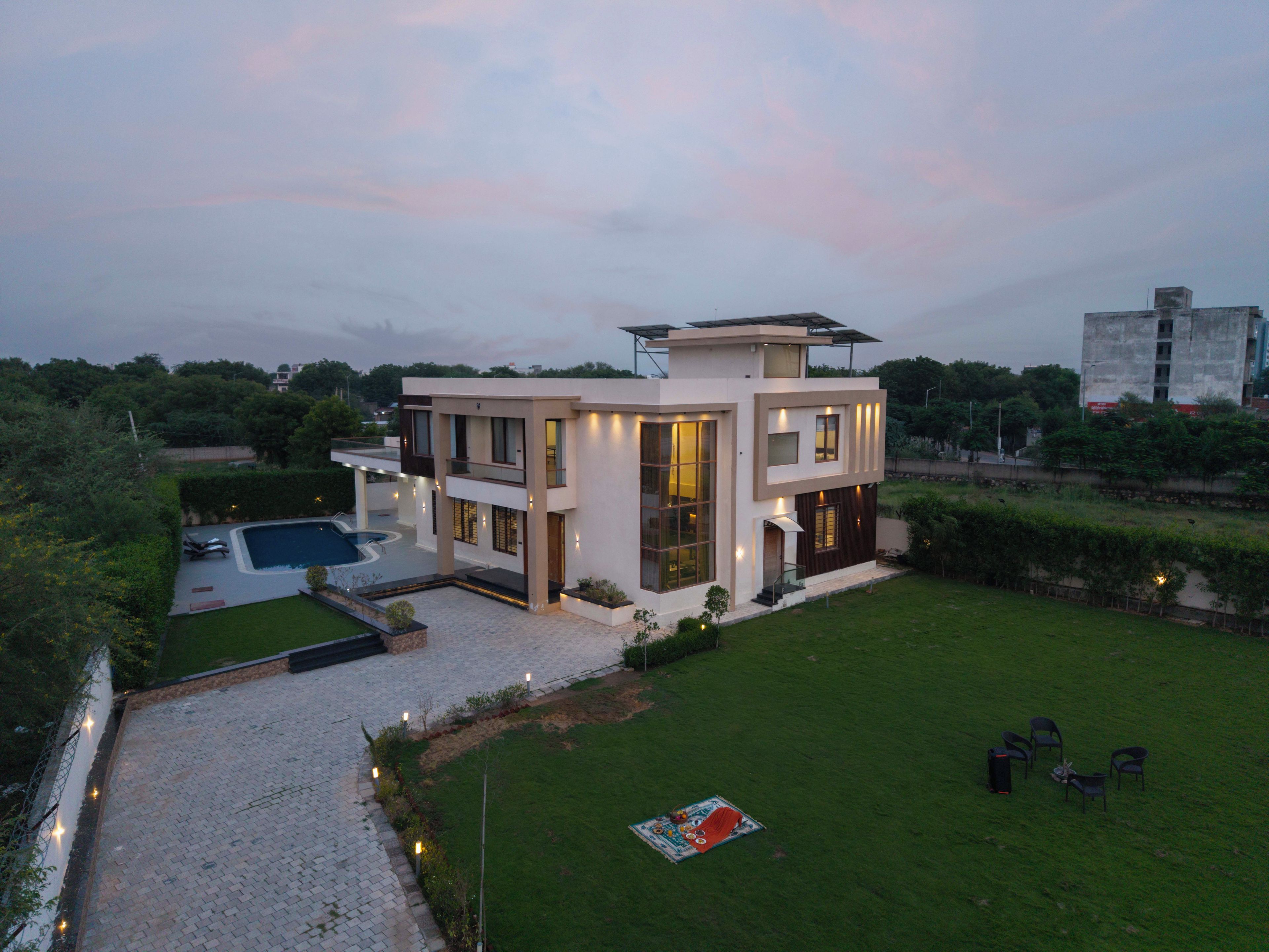 A modern two-story house with a swimming pool, a well-maintained lawn, and a patio area.