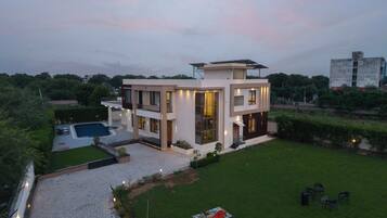 A modern two-story house with a swimming pool, a well-maintained lawn, and a patio area.