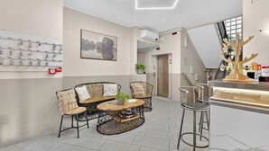A modern interior with a bar area, seating with patterned chairs, a coffee table, and a wall-mounted display. - Hotel Del Golfo (Laigueglia)