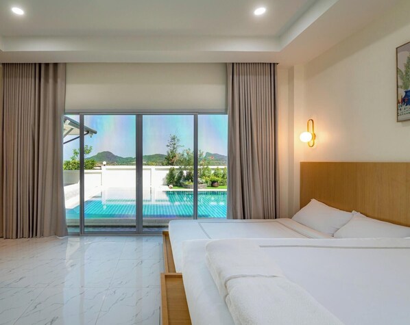 Quarto de hotel com cama, uma grande janela com cortinas, vista para uma piscina e luminária fixada na parede.