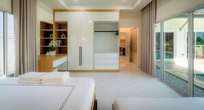 Ein modernes Hotelzimmer mit einem großen Bett, einem Einbauschrank, einer Sitzecke und einem Balkon mit Blick auf den Pool.