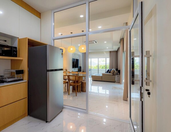 Eine moderne Küche mit Kühlschrank, Holzschränken und einem Essbereich mit Tisch und Stühlen.