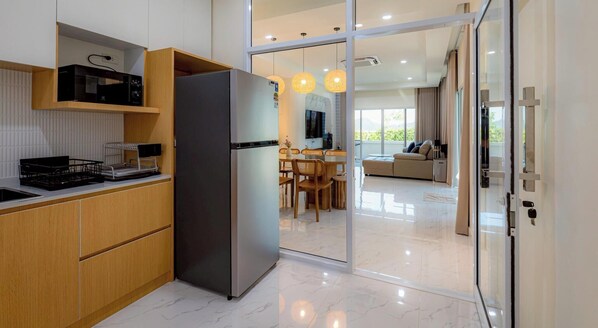 Eine moderne Küche mit Kühlschrank, Holzschränken und einem Essbereich mit Stühlen und einem Tisch.