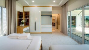 Ein modernes Hotelzimmer mit einem großen Bett, einem Einbauschrank, einer Sitzecke und einem Balkon mit Blick auf den Pool.