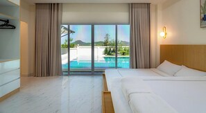 Ein Hotelzimmer mit Bett, Blick auf einen Swimmingpool und einem Balkon.
