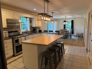 A modern kitchen with a central island, stainless steel appliances, and a dining area with a view.