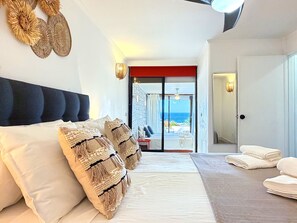 A bedroom with a bed, pillows, a view of the sea, a balcony, and a door. - Boho Sea by BeCherish (Albufeira)