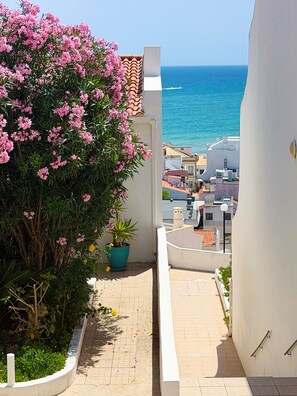 A narrow pathway leading to a balcony overlooking a coastal area with buildings and a clear sky. - Boho Sea by BeCherish (Albufeira)