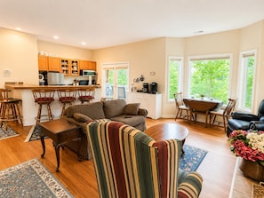 A spacious living area with a sofa, chairs, a dining table, and a kitchen area with wooden cabinets and a bar. - Millie's Lake Lure Lodge - Private Dock, Spacious, Bathrooms for Every Bedroom! (Lake Lure)