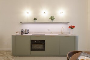 Eine moderne Küche mit Backofen, Spüle und einer Arbeitsplatte, auf der ein Kaffeemaschine und eine Pflanze stehen.
