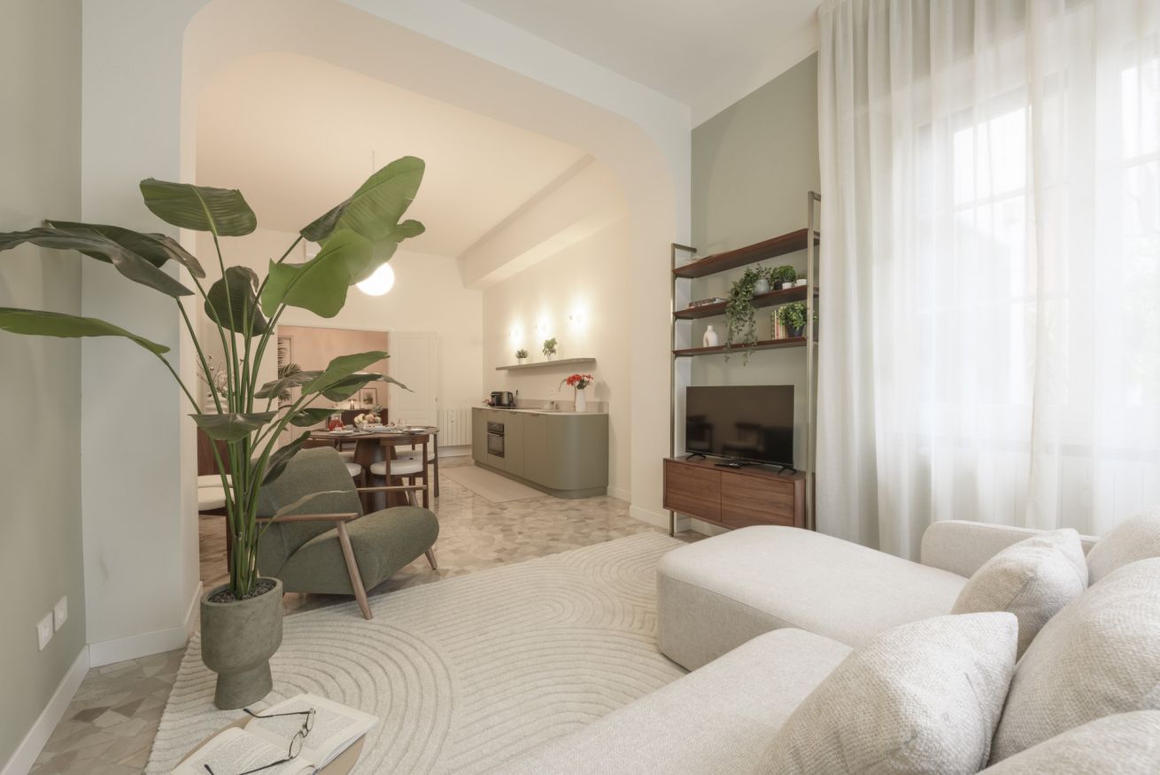 A modern living room with a sofa, a coffee table, a plant, and a TV stand.