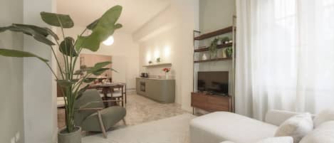 A modern living room with a sofa, a coffee table, a plant, and a TV stand.