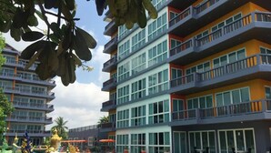 Un hotel de varios pisos con piscina, balcones y zonas de estar al aire libre.