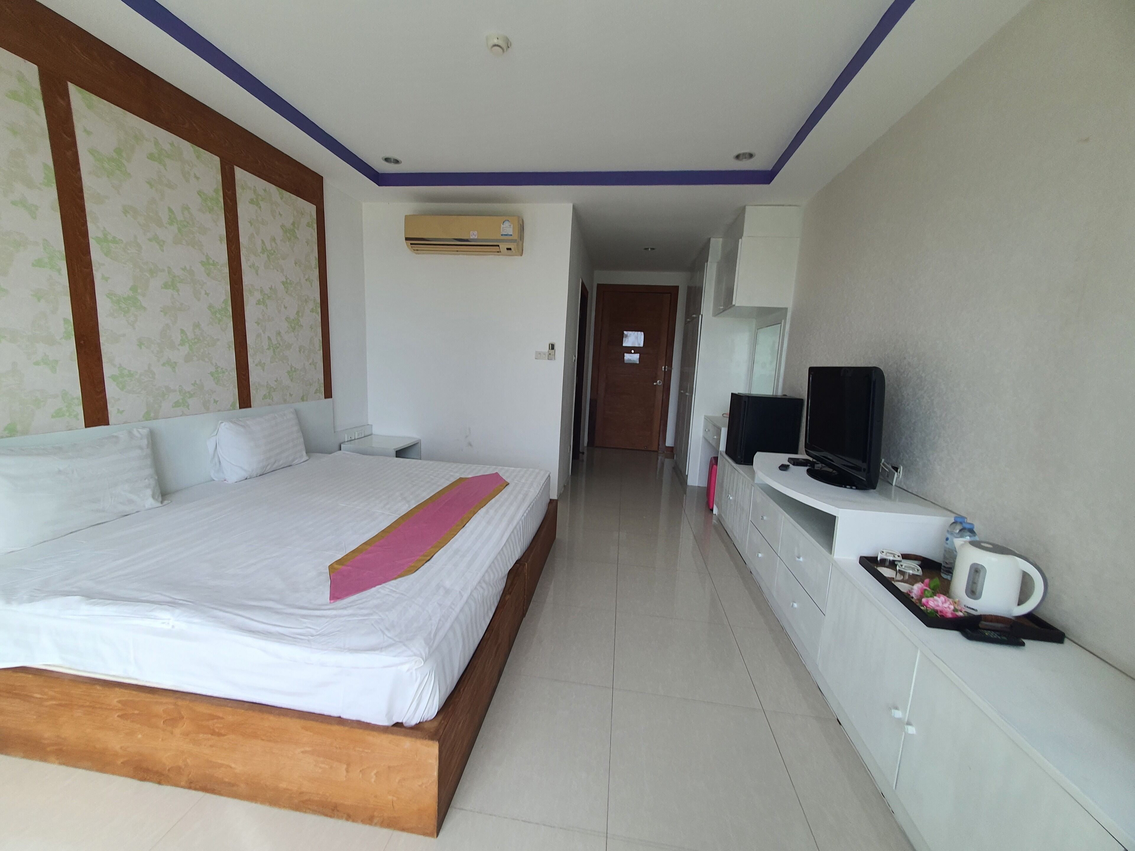 A hotel room with a bed, a TV, a coffee maker, and a water dispenser.
