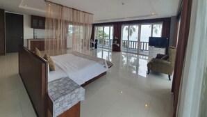 Un dormitorio espacioso con una cama grande, un balcón con vistas al mar y un televisor.