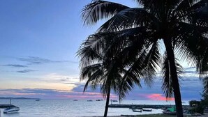 Una playa con palmeras, barcos y un atardecer.
