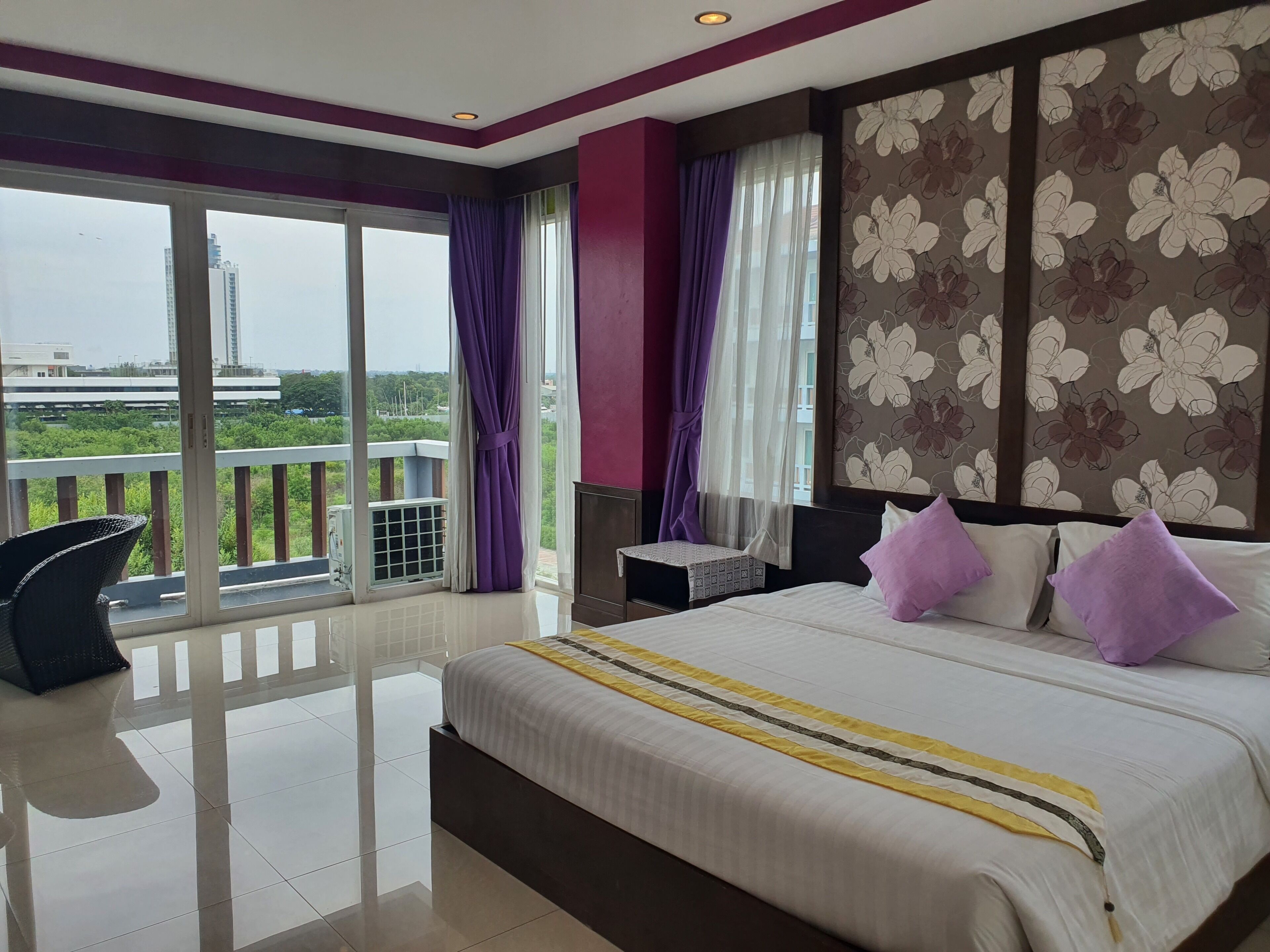 Een hotelkamer met een groot bed, een zithoek en een balkon met uitzicht.