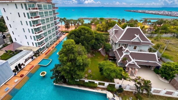 Un resort con piscina, un edificio grande con balcones y vistas al océano.