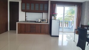 A modern kitchen with a built-in microwave, a refrigerator, and a window with curtains. - Sunday Sand Beach Pattaya (Sattahip)