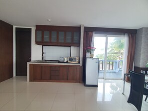 A modern kitchen with a built-in microwave, a refrigerator, and a window with curtains. - Sunday Sand Beach Pattaya (Sattahip)