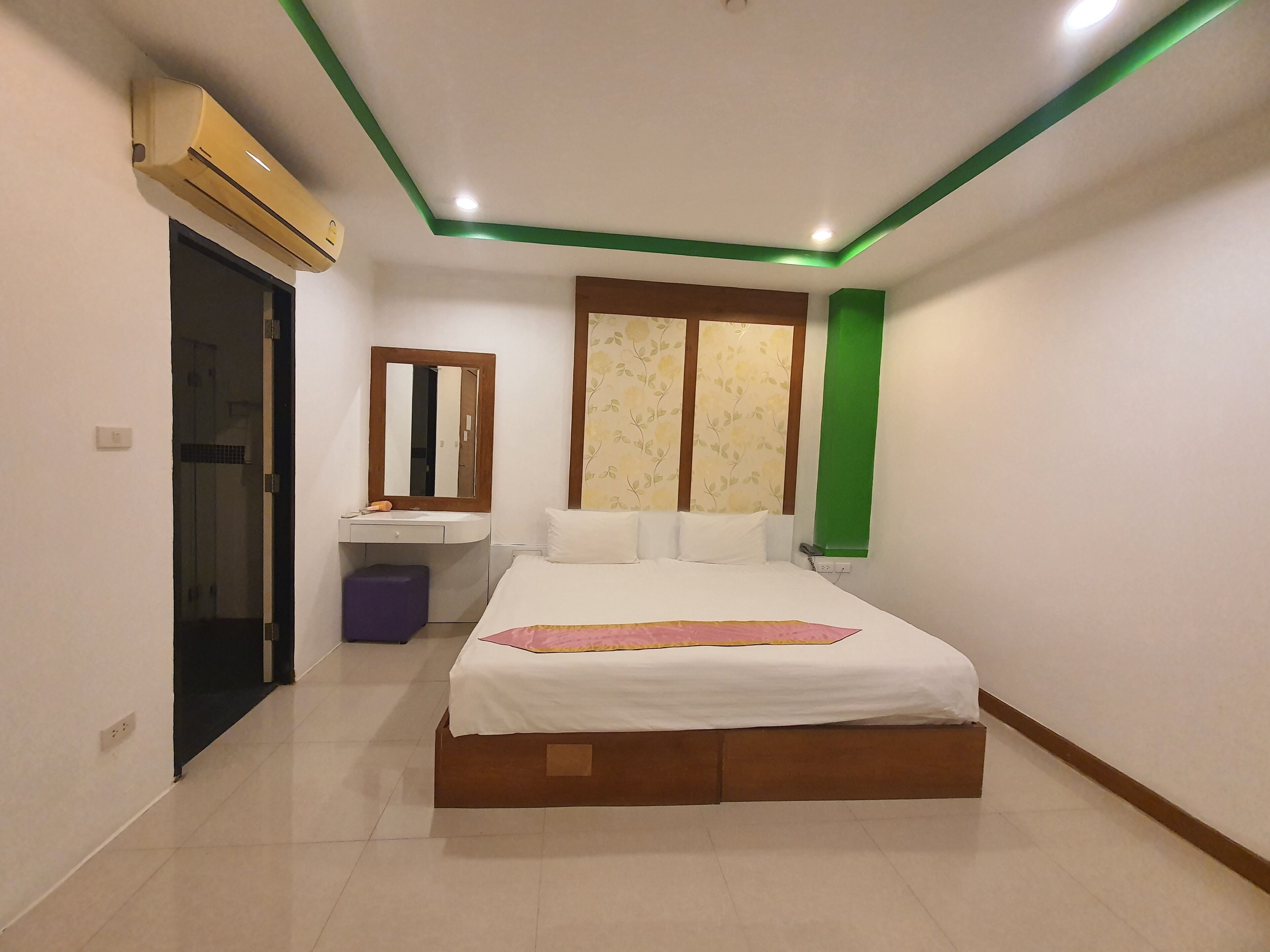 A bedroom with a bed, a vanity with a mirror, a toilet, and a shower.