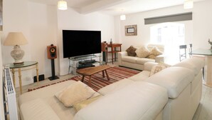 Een woonkamer met een flatscreen televisie, bank, salontafel en een glazen tv-meubel.