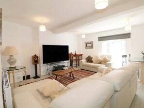 A living room with a flat-screen TV, sofa, coffee table, and a glass TV stand. - The Old Granary (Southampton)