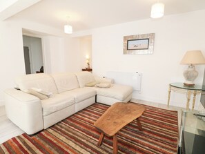 A living room with a sectional sofa, a wooden coffee table, a striped rug, a lamp, and a framed picture on the wall. - The Old Granary (Southampton)